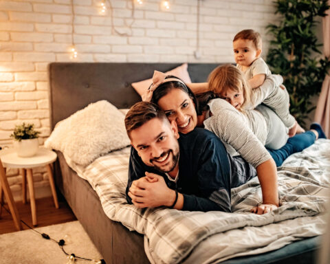 Young and happy family playing in bedroom